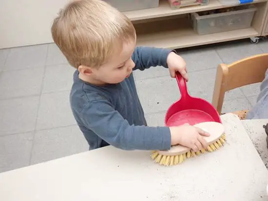 Niño de 2 años usando materiales de limpieza